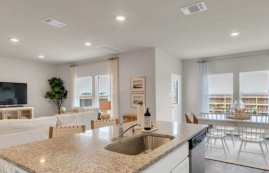 Kitchen with a sink, open floor plan, stainless steel dishwasher, white cabinetry, and recessed lighting Kitchen with a sink, open floor plan, stainless steel dishwasher, white cabinetry, and recessed lighting