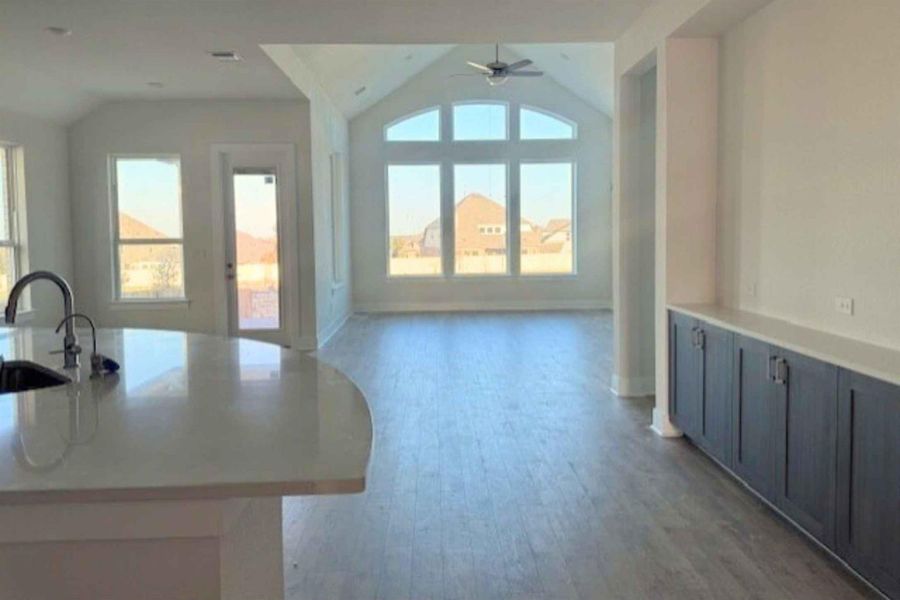 Living room featuring light wood finished floors, ceiling fan, vaulted ceiling, and plenty of natural light