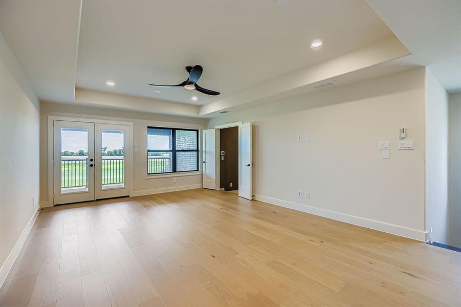 Unfurnished room featuring a tray ceiling, a ceiling fan, light wood-style flooring, french doors, and recessed lighting