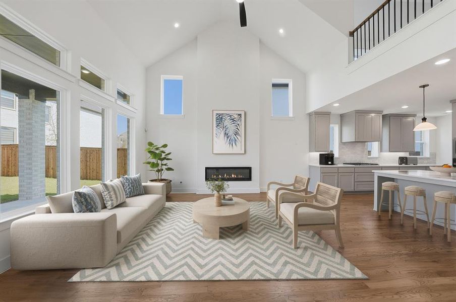 Living room with high vaulted ceiling, plenty of natural light, a glass covered fireplace, dark wood-style flooring, and recessed lighting Living room with high vaulted ceiling, plenty of natural light, a glass covered fireplace, dark wood-style flooring, and recessed lighting