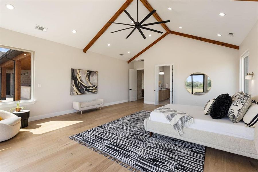Bedroom featuring light wood-style floors, beamed
ceiling, high vaulted ceiling, connected bathroom,
and recessed lighting Bedroom featuring light wood-style floors, beamed
ceiling, high vaulted ceiling, connected bathroom,
and recessed lighting
