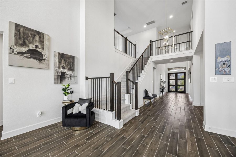 Grand two-story foyer featuring soaring ceilings, elegant staircase and beautiful wood-look tile flooring