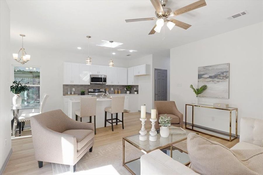 Living room with ceiling fan with notable chandelier and light hardwood / wood-style floors