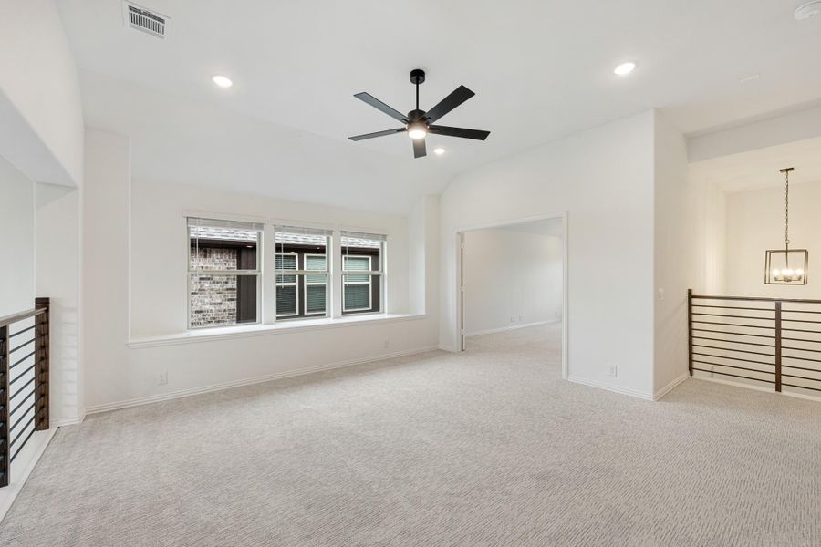 Spacious upstairs loft with carpet, vaulted ceiling, ceiling fan, and metal railing overlooking lower level Spacious upstairs loft with carpet, vaulted ceiling, ceiling fan, and metal railing overlooking lower level