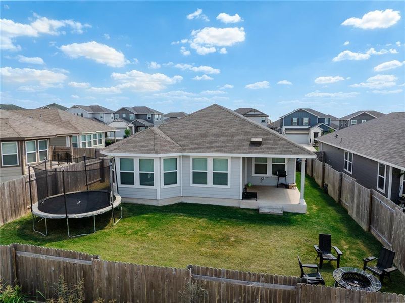 Back of property with a patio, a shingled roof, a trampoline, a residential view, and a fenced backyard