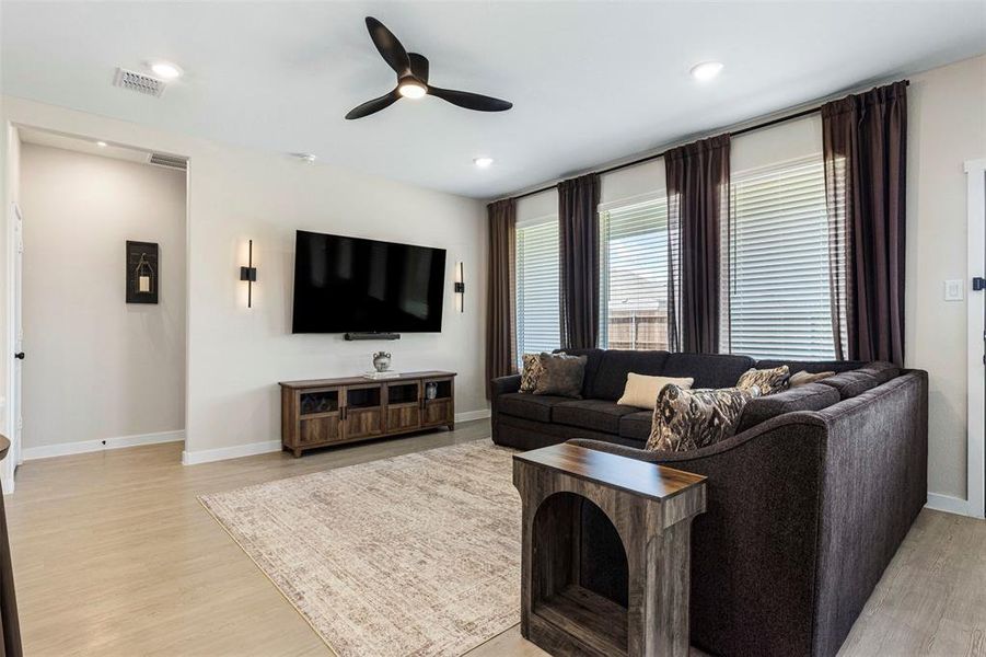 Open-concept living area featuring light wood-finish flooring and a contemporary ceiling fan Open-concept living area featuring light wood-finish flooring and a contemporary ceiling fan