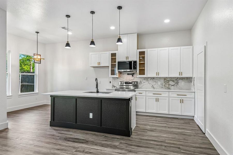 Contemporary kitchen featuring a dark-toned island with a white countertop and integrated sink