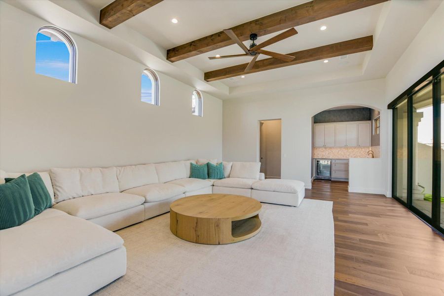 Living room with arched walkways, recessed lighting, wood finished floors, ceiling fan, and wine cooler
