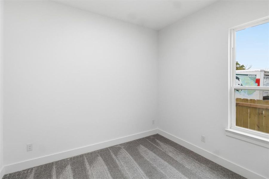Carpeted spare room featuring baseboards