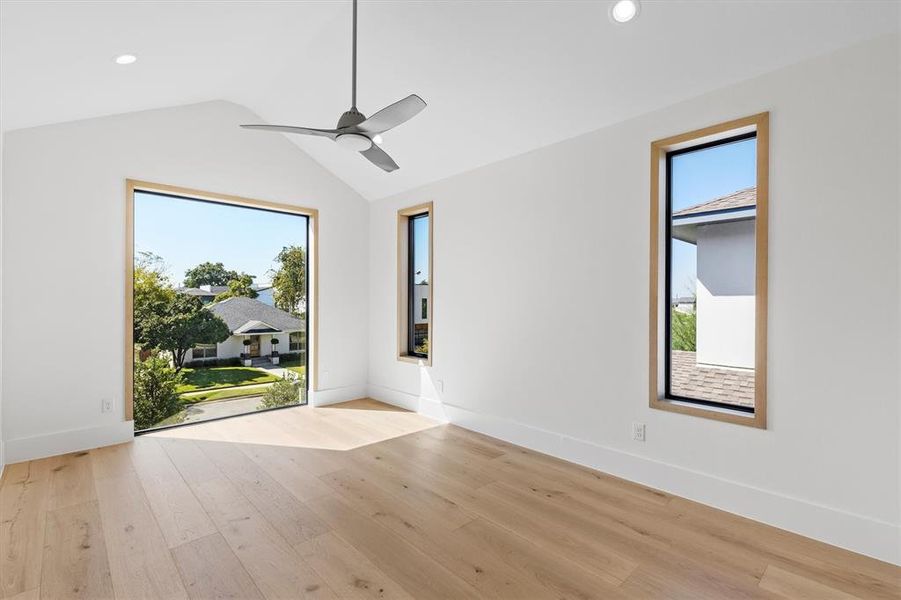 Unfurnished room with a healthy amount of sunlight, light hardwood / wood-style floors, and vaulted ceiling