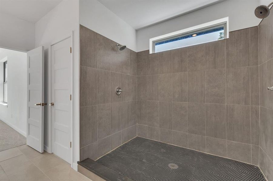 Bathroom with tiled shower and tile patterned floors