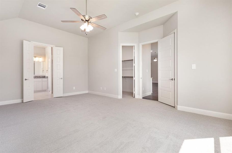 Unfurnished bedroom featuring light carpet, ensuite bath, a walk in closet, and ceiling fan Unfurnished bedroom featuring light carpet, ensuite bath, a walk in closet, and ceiling fan