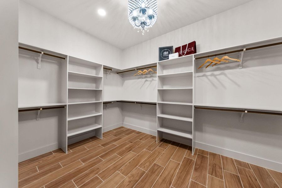 Custom shelving and hanging space with elegant tile flooring define this spacious walk-in closet.
