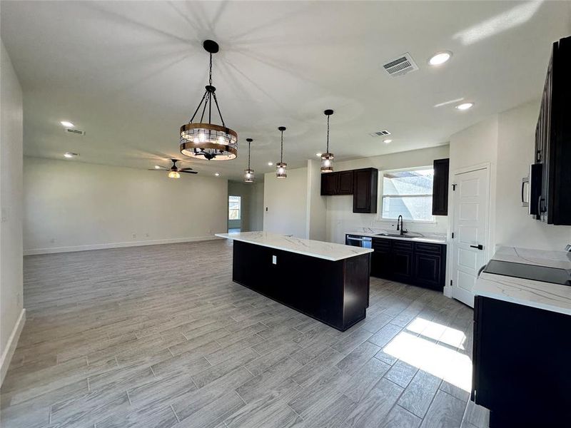 Kitchen featuring light hardwood / wood-style flooring, sink, light stone counters, range, and a kitchen island