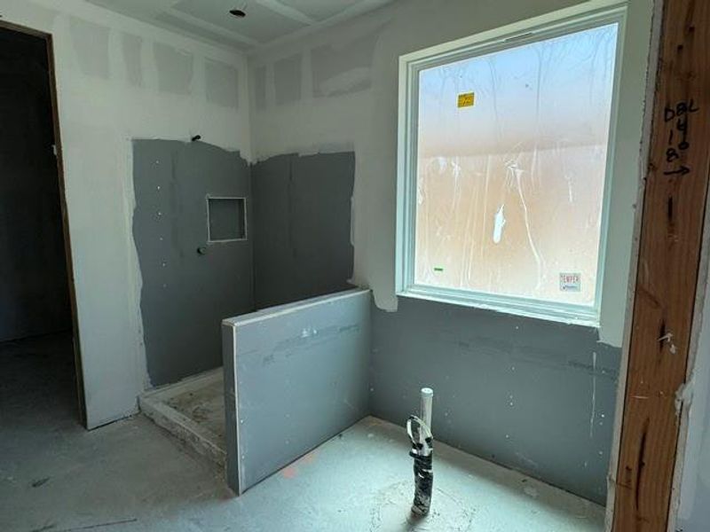 A window bathes this future bathroom in natural light, showcasing the shower stall's early construction. A window bathes this future bathroom in natural light, showcasing the shower stall's early construction.