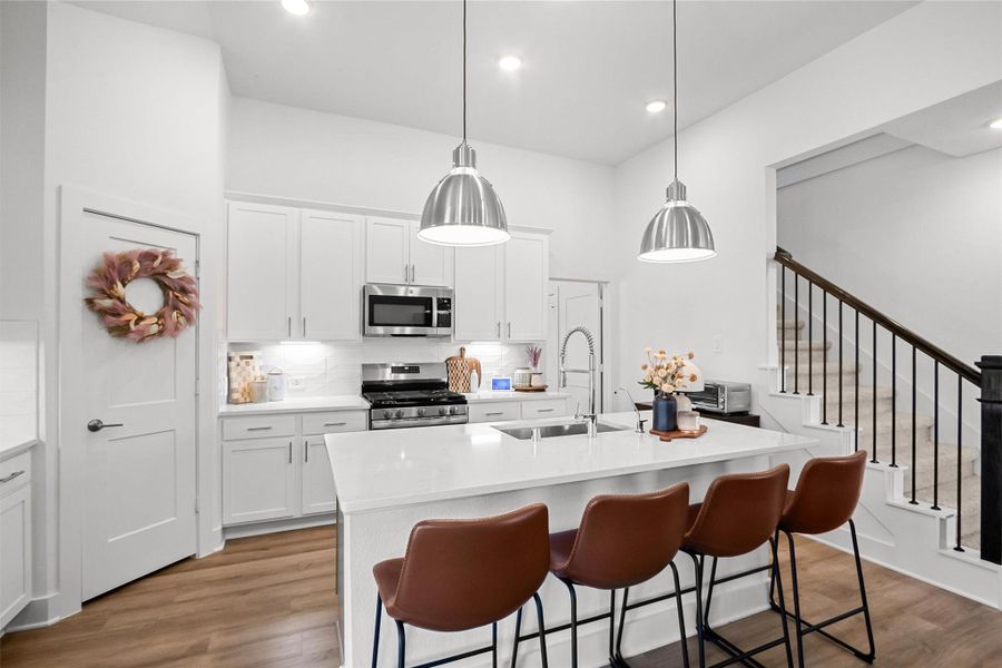 A kitchen designed for gathering! The oversized island offers generous prep space and seating for four, complemented by crisp white cabinetry, stainless steel appliances, modern pendant lighting, and an open layout perfect for entertaining.