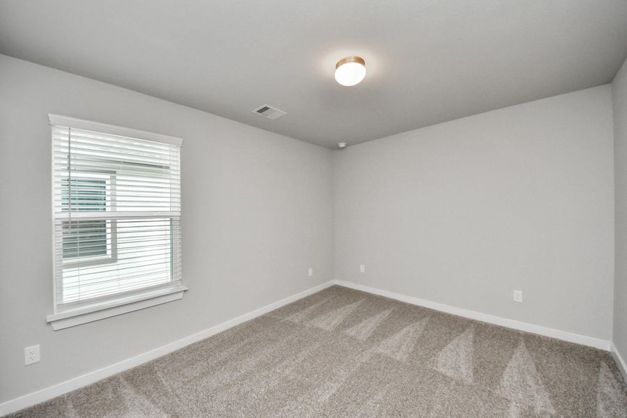 Secondary bedroom features plush carpeting, large windows that let in plenty of natural light, bright paint, and spacious closets. Sample photo of completed home with similar floor plan. Actual colors and selections may vary.