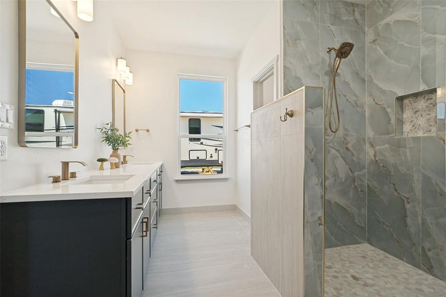 Modern en-suite bathroom in primary bedroom featuring a double vanity with dark cabinetry and white countertops and a gorgeous spa-like shower area.