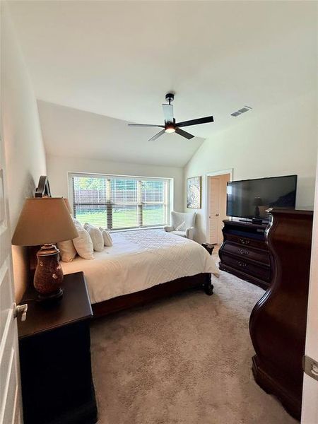 Carpeted room with a vaulted ceiling and a ceiling fan with integrated lighting Carpeted room with a vaulted ceiling and a ceiling fan with integrated lighting