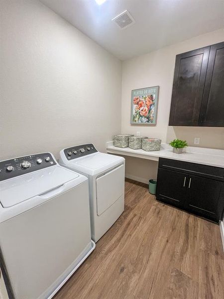 Laundry room featuring cabinet space, washer and dryer, light wood-type flooring, and an office area