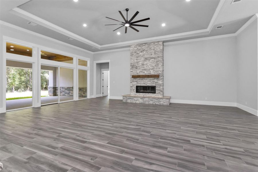 The Family Room features a modern inset gas fireplace with stone running all the way to the incredibly high ceilings, a tray ceiling with an oversized ceiling fan, beautiful crown moldings, along with two shielded CAT6A (Ethernet/Data) and shielded coaxial (TV) cables.