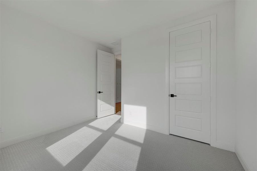Unfurnished bedroom featuring light colored carpet and baseboards