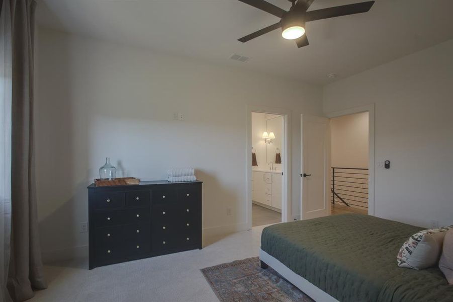 Carpeted bedroom featuring connected bathroom and ceiling fan