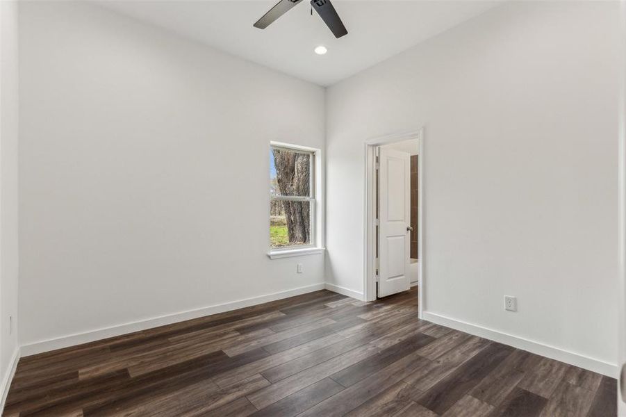 Empty room featuring ceiling fan and dark hardwood / wood-style flooring