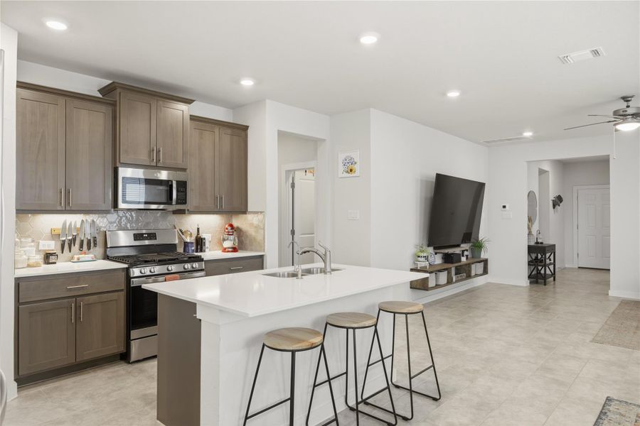 Kitchen with stainless steel appliances, ceiling fan, a kitchen island with sink, a kitchen breakfast bar, and recessed lighting