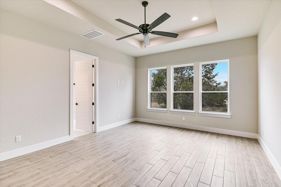 Spare room with wood finish floors, ceiling fan, and a raised ceiling