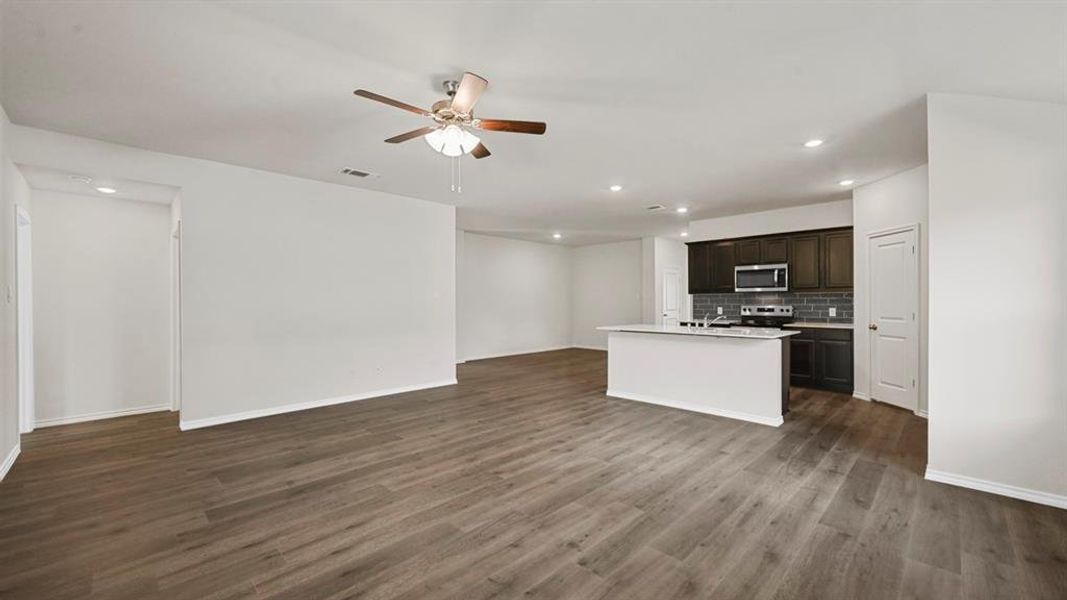 Open-concept living space featuring wood-finish flooring and a ceiling fan Open-concept living space featuring wood-finish flooring and a ceiling fan