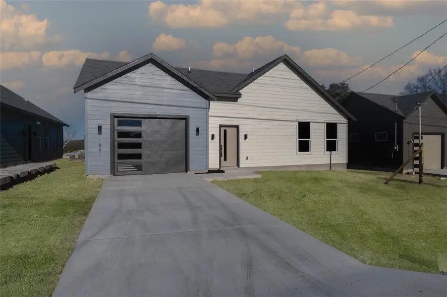 View of front of home featuring driveway, a garage, and a front lawn