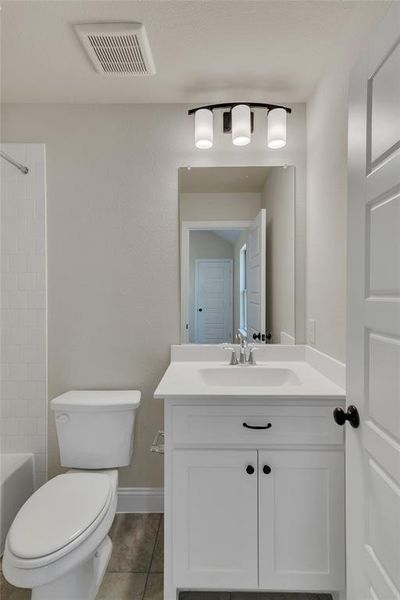 Full bathroom featuring shower / bath combination, vanity, tile patterned floors, and toilet