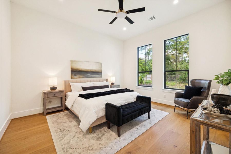 Secondary guest suite on the first floor with white oak wood flooring, recessed lighting, and large windows for natural light.