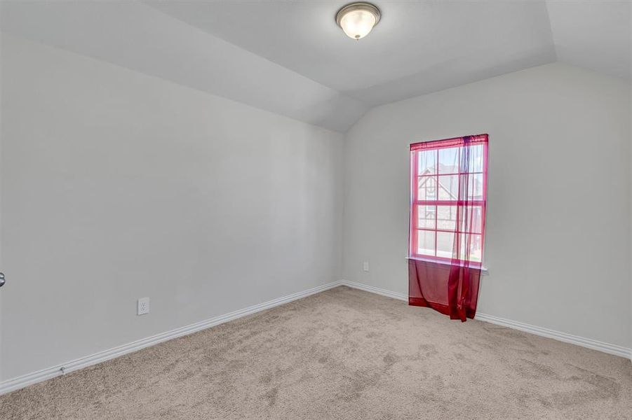 Carpeted empty room featuring lofted ceiling