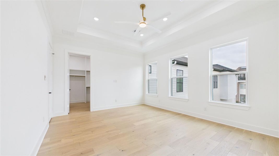 Secondary bedroom with three large windows allow plenty of natural light. There's an open doorway leading to a walk-in closet.