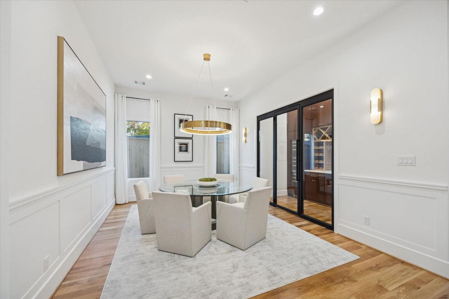 Designed with both everyday meals and entertaining in mind, the dining room offers comfortable proportions and easy flow to the kitchen and wine room through sleek glass doors. Thoughtful wall paneling, designer lighting, and soft natural light create a setting that feels polished yet welcoming for gatherings large or small. Designed with both everyday meals and entertaining in mind, the dining room offers comfortable proportions and easy flow to the kitchen and wine room through sleek glass doors. Thoughtful wall paneling, designer lighting, and soft natural light create a setting that feels polished yet welcoming for gatherings large or small.