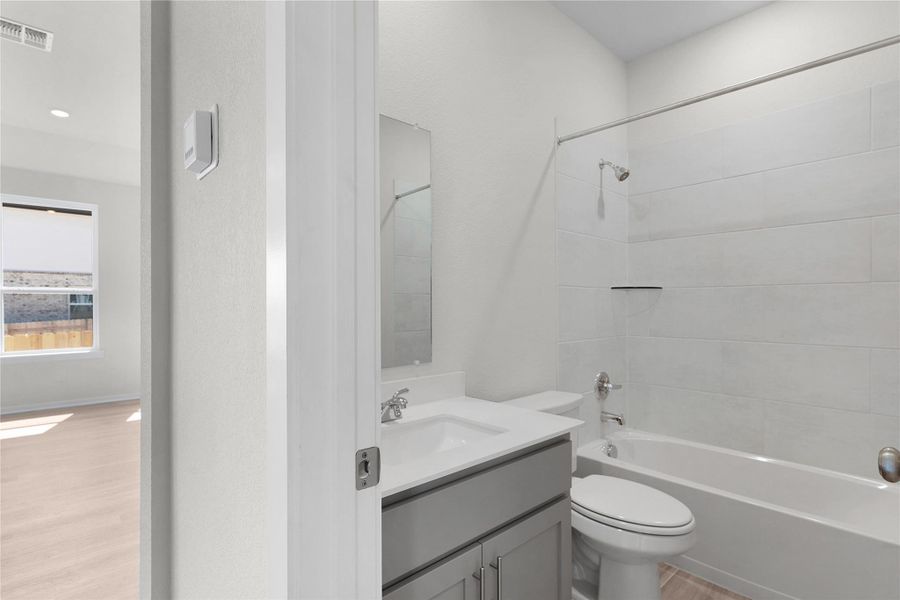 Full bath with light wood-type flooring, vanity, and bathtub / shower combination