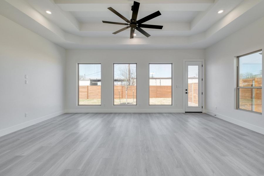 Unfurnished room with a tray ceiling, recessed lighting, baseboards, and light wood-type flooring