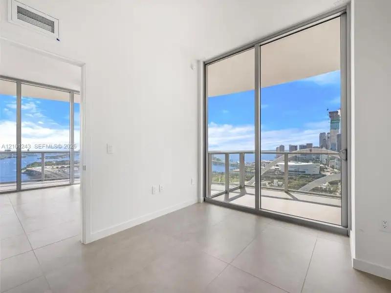 Floor-to-ceiling glass sliding doors, large-format tile flooring, and metal-framed balcony railings Floor-to-ceiling glass sliding doors, large-format tile flooring, and metal-framed balcony railings