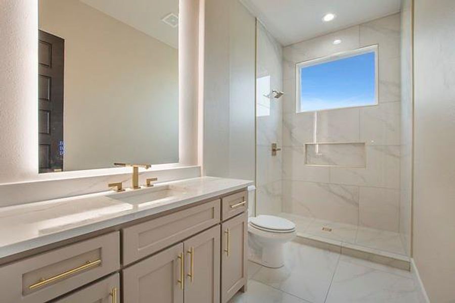 Bathroom featuring a tile shower, vanity, and toilet