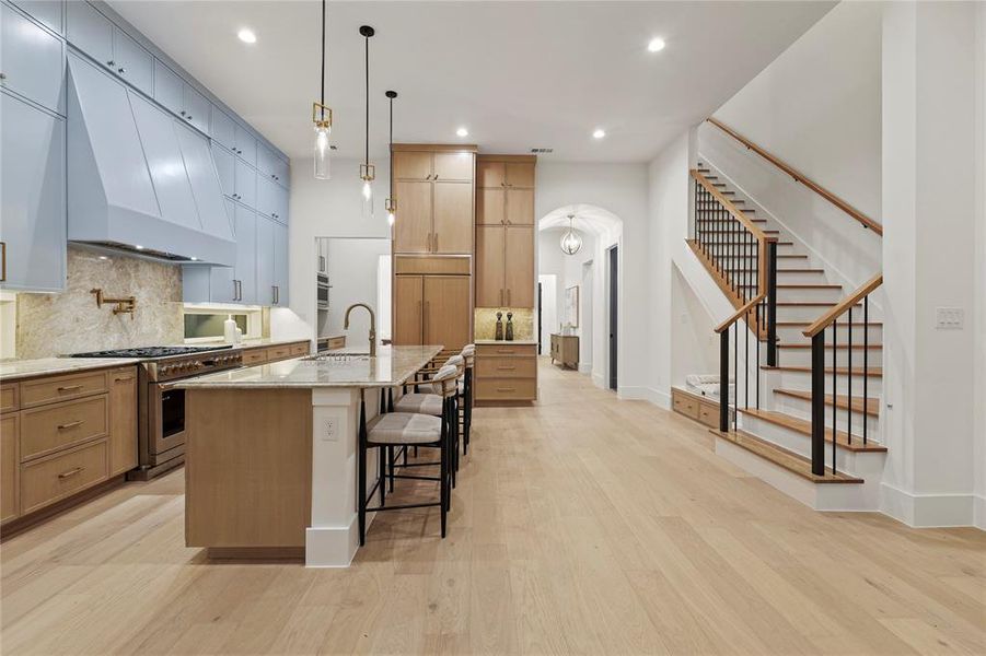 Kitchen with a breakfast bar, custom range hood, tasteful backsplash, stainless steel range, and light stone countertops