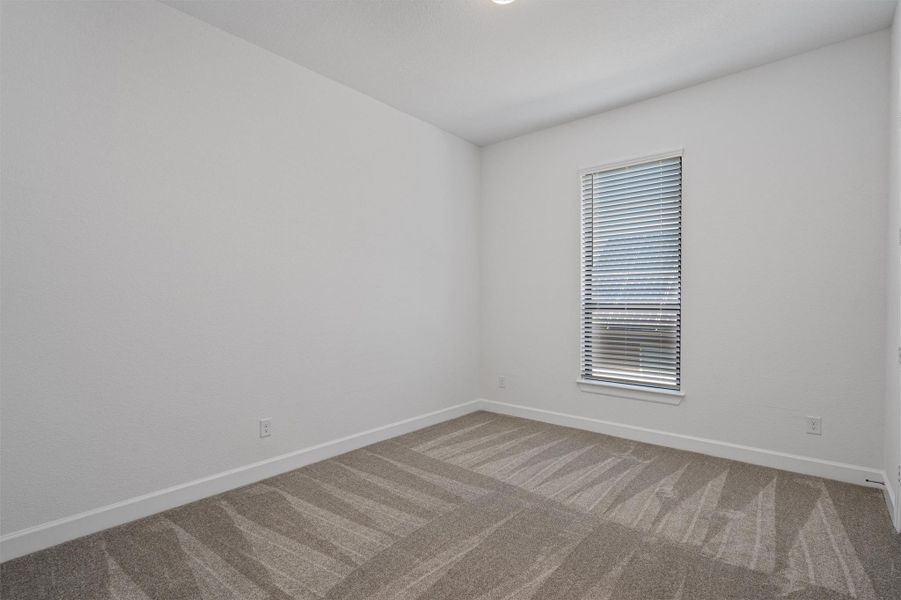 Bright room featuring a single window with blinds, light-colored walls, and patterned carpeting