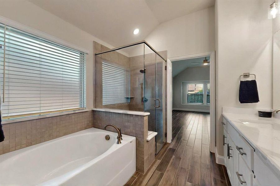 Full bathroom with vaulted ceiling, vanity, a bath, a shower stall, and ceiling fan