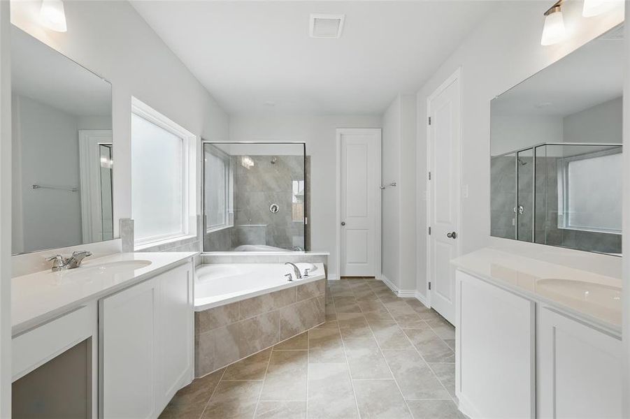 Full bathroom featuring two vanities, a shower stall, a bath, a sink, and visible vents Full bathroom featuring two vanities, a shower stall, a bath, a sink, and visible vents