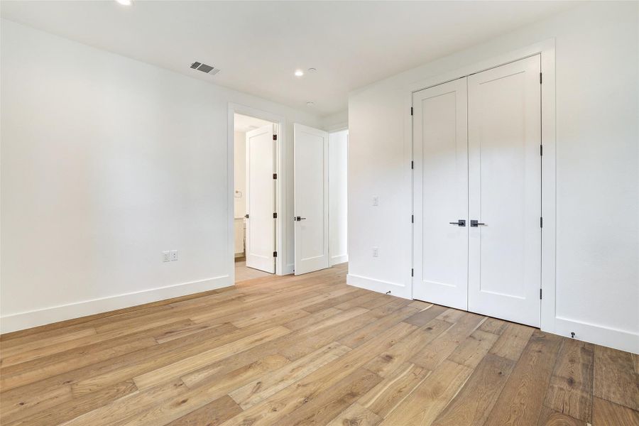 Unfurnished bedroom featuring light wood-type flooring, recessed lighting, baseboards, a closet, and ensuite bath