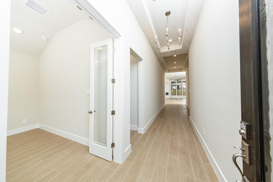 A bright and open interior entryway focuses on modern design and natural light. The space is amplified by high ceilings, recessed lighting, gorgeous wood-look tile flooring - creating an airy and welcoming first impression.