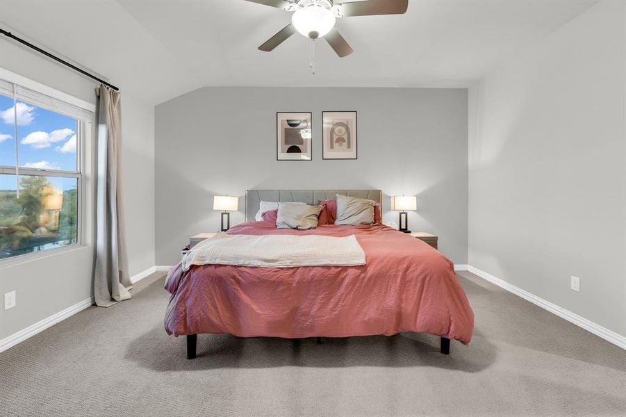 Carpeted bedroom featuring vaulted ceiling and ceiling fan