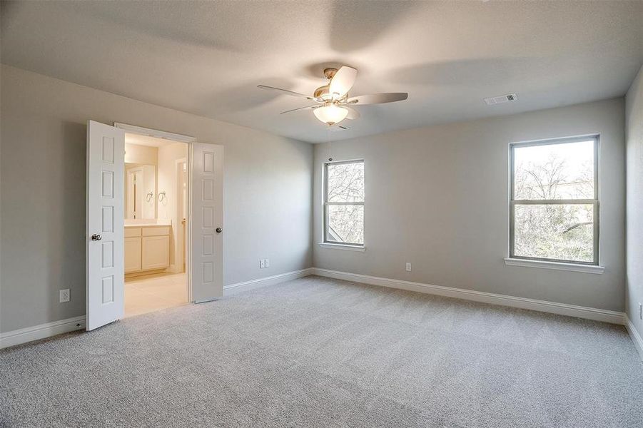 Unfurnished bedroom featuring light colored carpet, ceiling fan, and connected bathroom Unfurnished bedroom featuring light colored carpet, ceiling fan, and connected bathroom