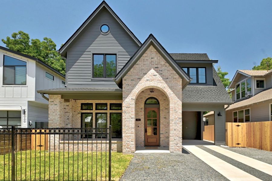 A charming facade combines light brick and siding, featuring an inviting arched entryway and modern window design. A charming facade combines light brick and siding, featuring an inviting arched entryway and modern window design.